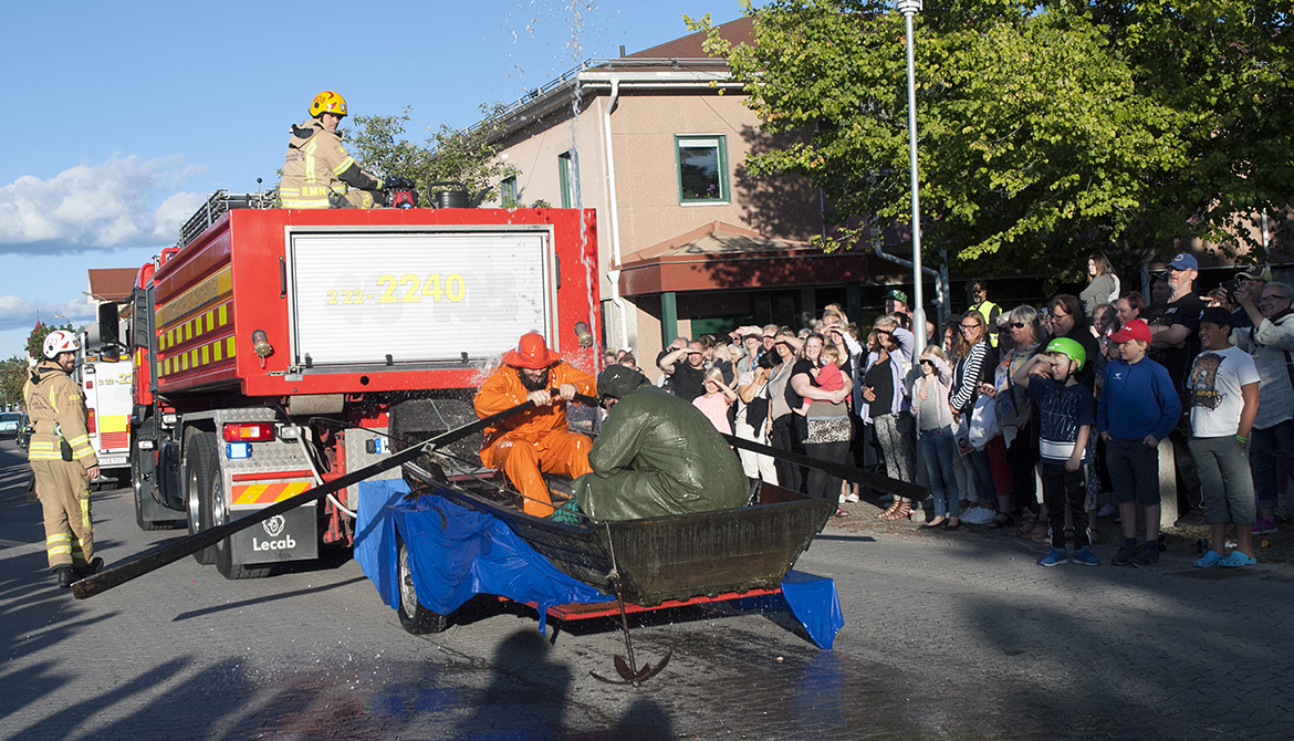 Två personer i vattenstråle på en vagn bakom ett räddningsfordon