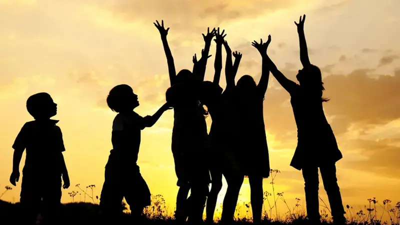 Barn som sträcker upp händerna mot himlen.