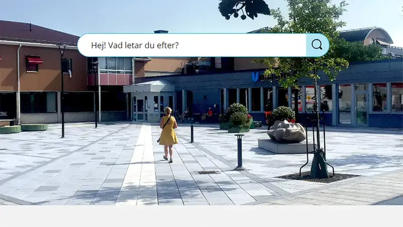 Bild på torget i Kil med biblioteket i bakgrunde. Kvinna går på plattor på väg till biblioteket.